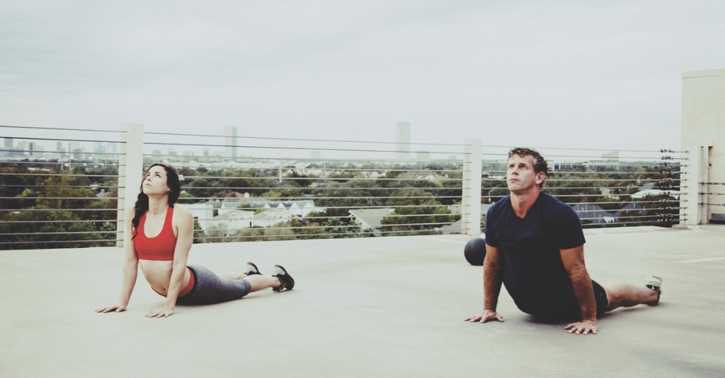 Brice Remaley and a client holding a cobra stretch on a Houston rooftop